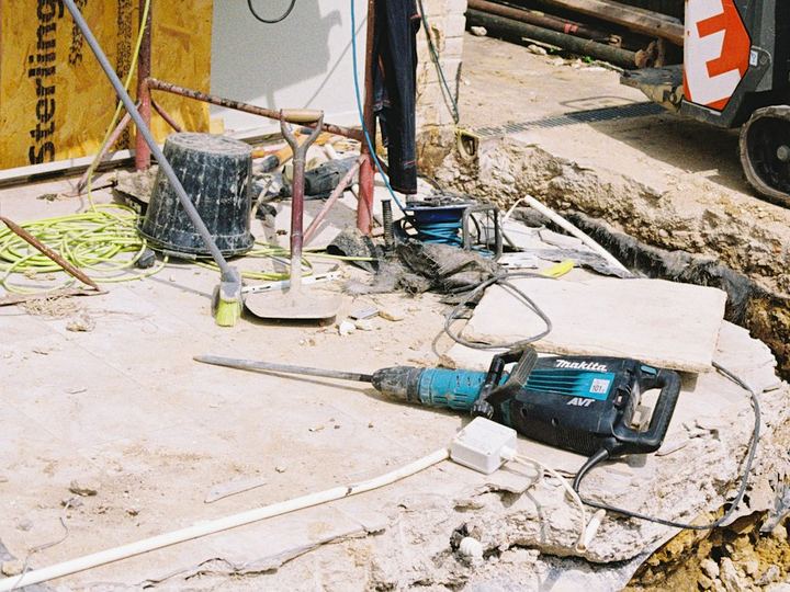 Breaker and broken-out concrete slab beside a new foundation trench