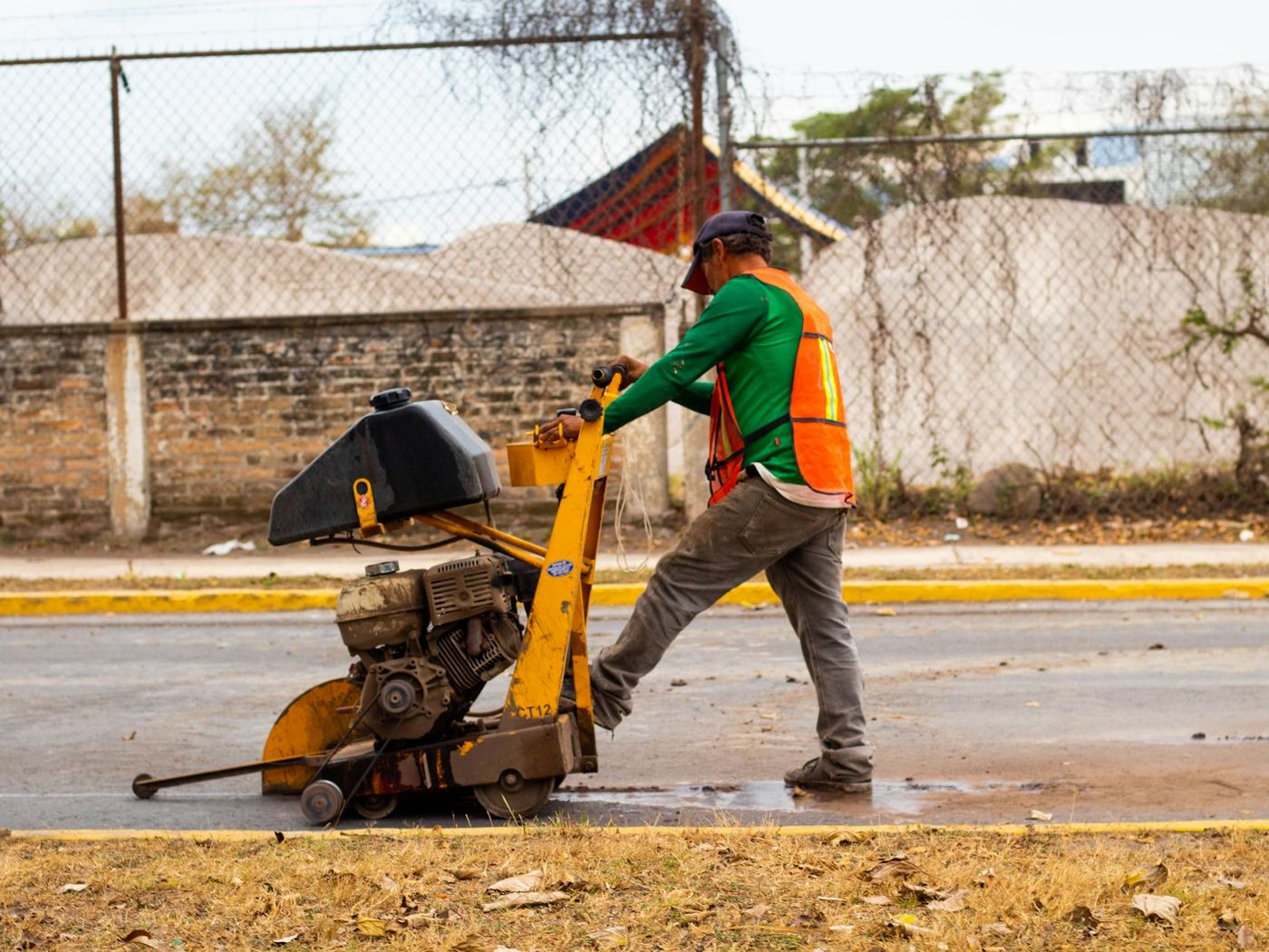 Operator cutting a road surface with a walk-behind floor saw