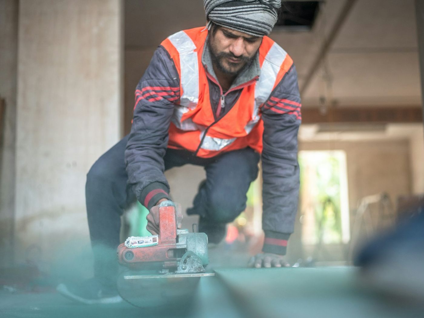 Operator cutting a concrete floor slab indoors with a hand-held saw